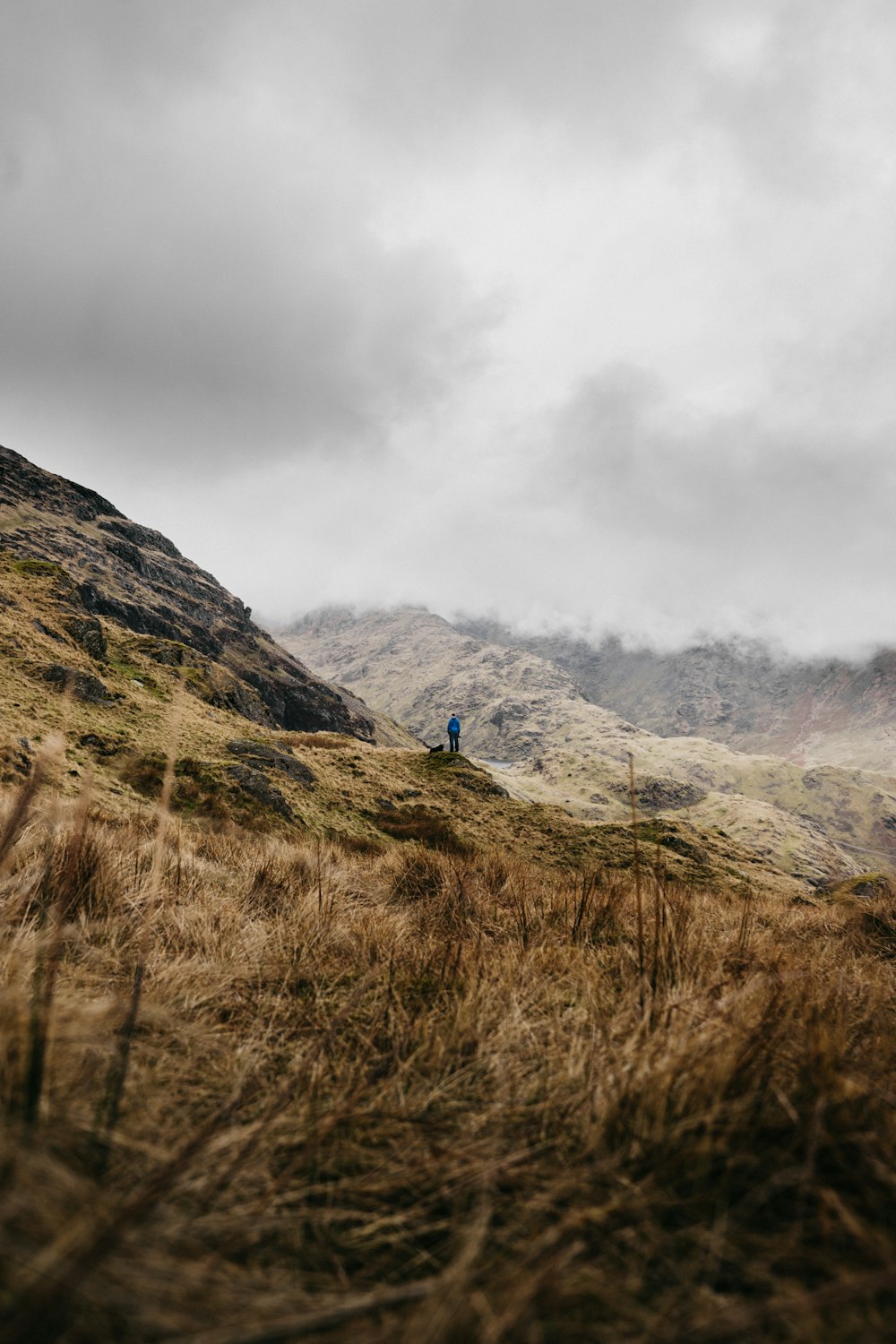 person standing on mountain under cloudy sky