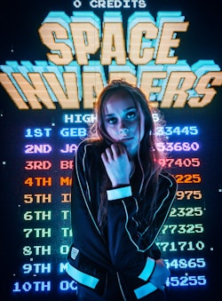 woman posing for photo in front of Space Invaders scoreboard