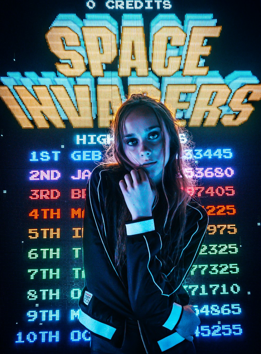 mulher posando para foto em frente ao placar do Space Invaders
