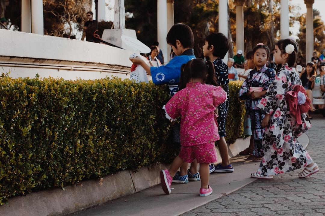 children wearing yukata standing near bush,