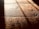 Warm, textured wooden floorboards with visible grain and shadows cast diagonally across the surface, creating a contrast between light and dark areas.
