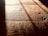 Warm, textured wooden floorboards with visible grain and shadows cast diagonally across the surface, creating a contrast between light and dark areas.