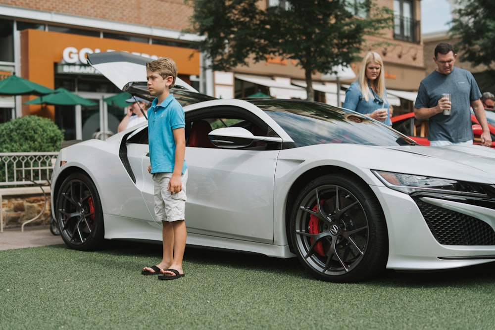 boy standing near white sports car