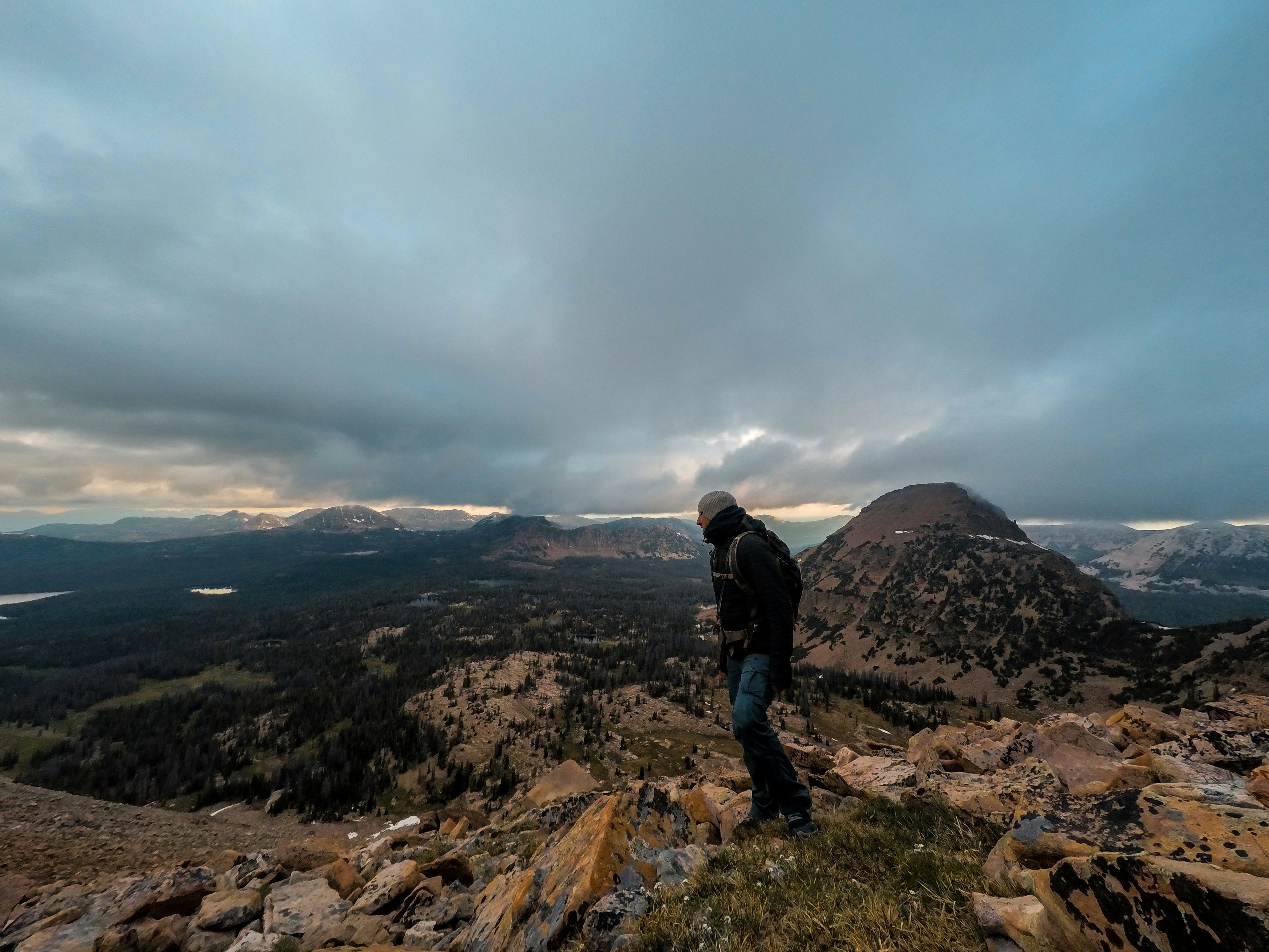 man standing on rocky mountain under gray cloudy sky