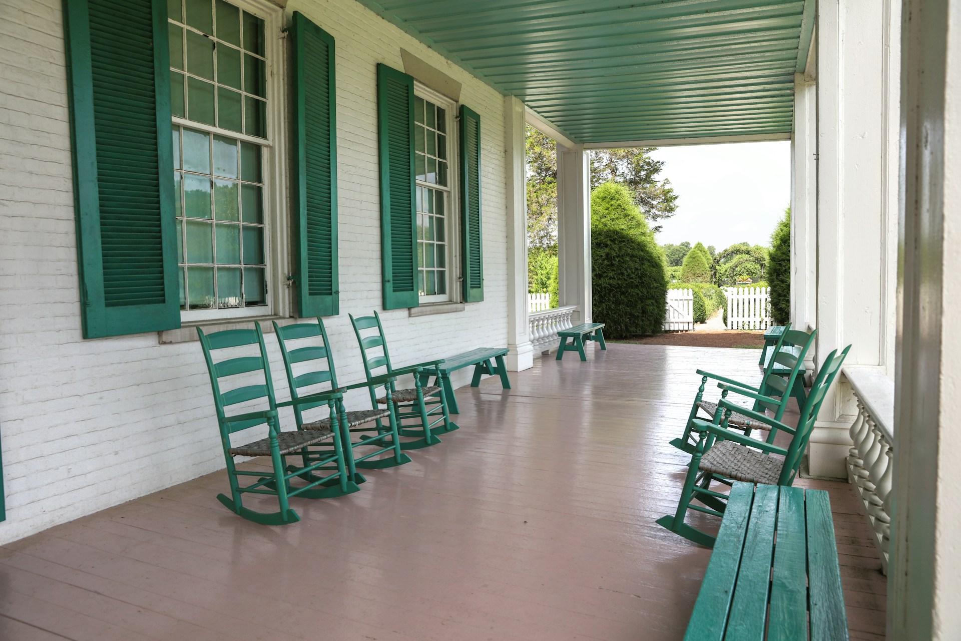 An inviting porch overlooking the lowcountry coast, furnished with classic rocking chairs and soft cushions in layered neutrals.