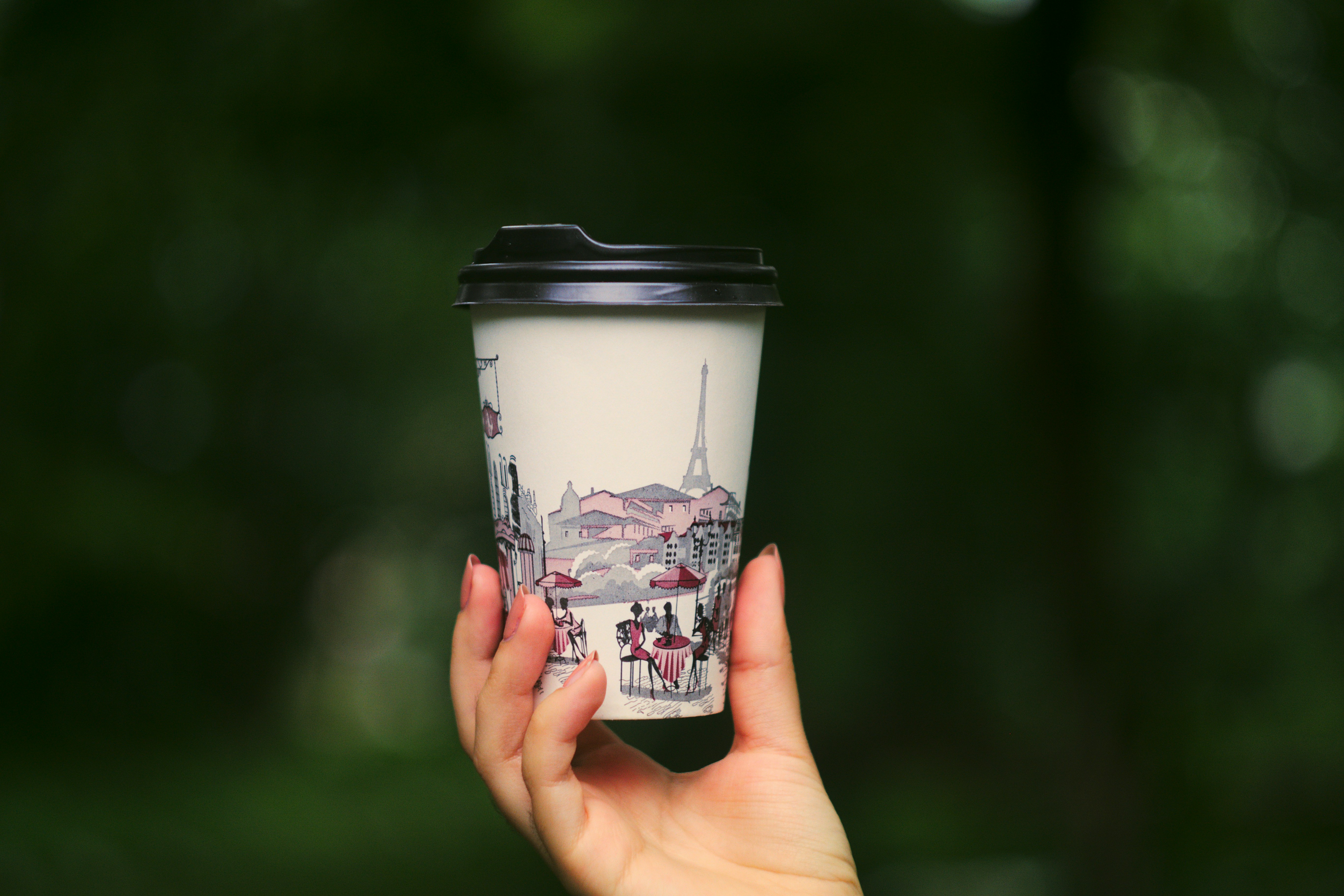 person holding white and black disposable coffee cup