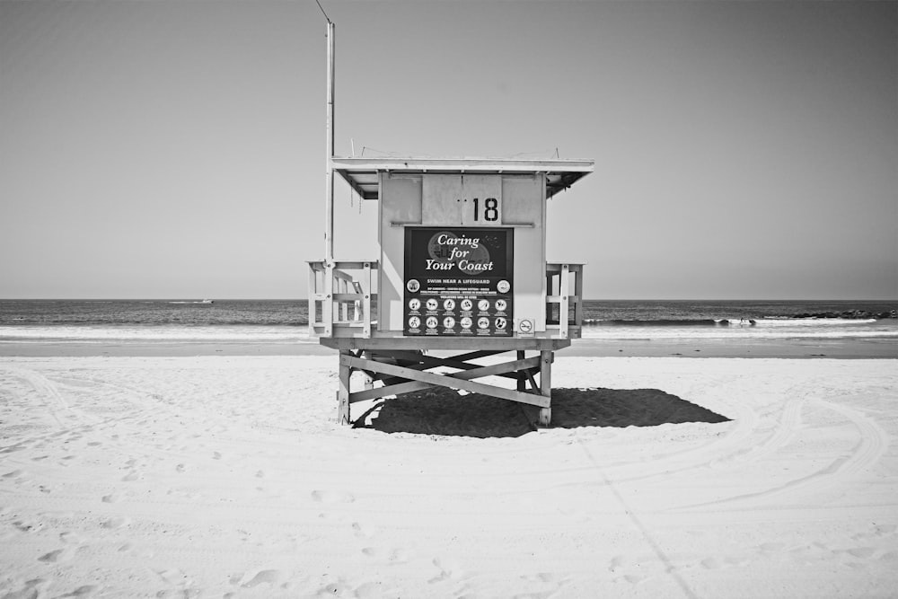 grayscale photography of life guard house on beach shore