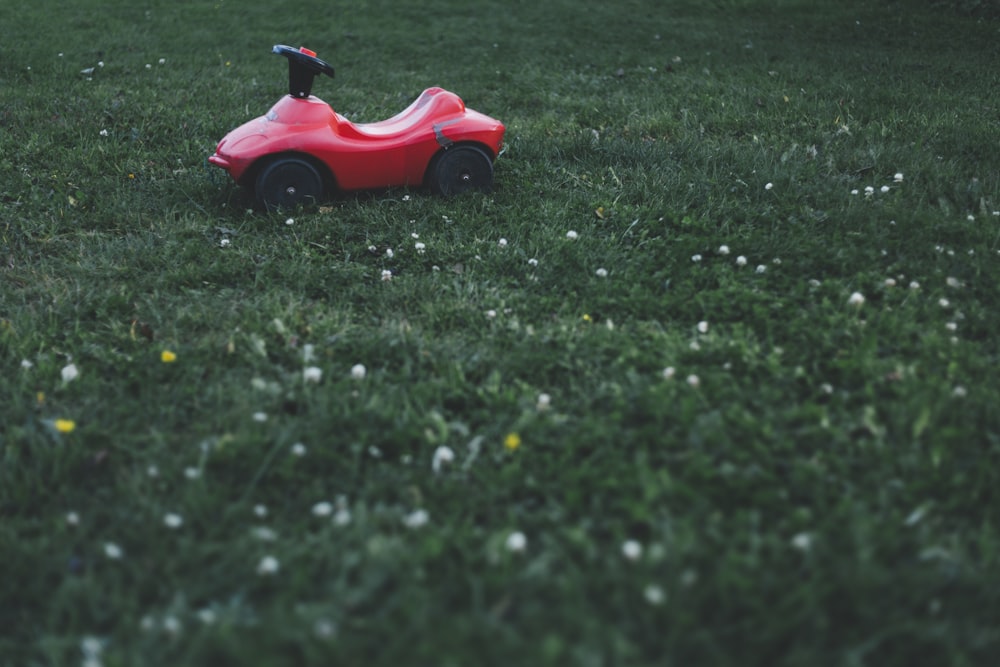 red ride-on toy car on grass field