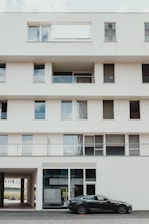 black sedan parked in front of white concrete building