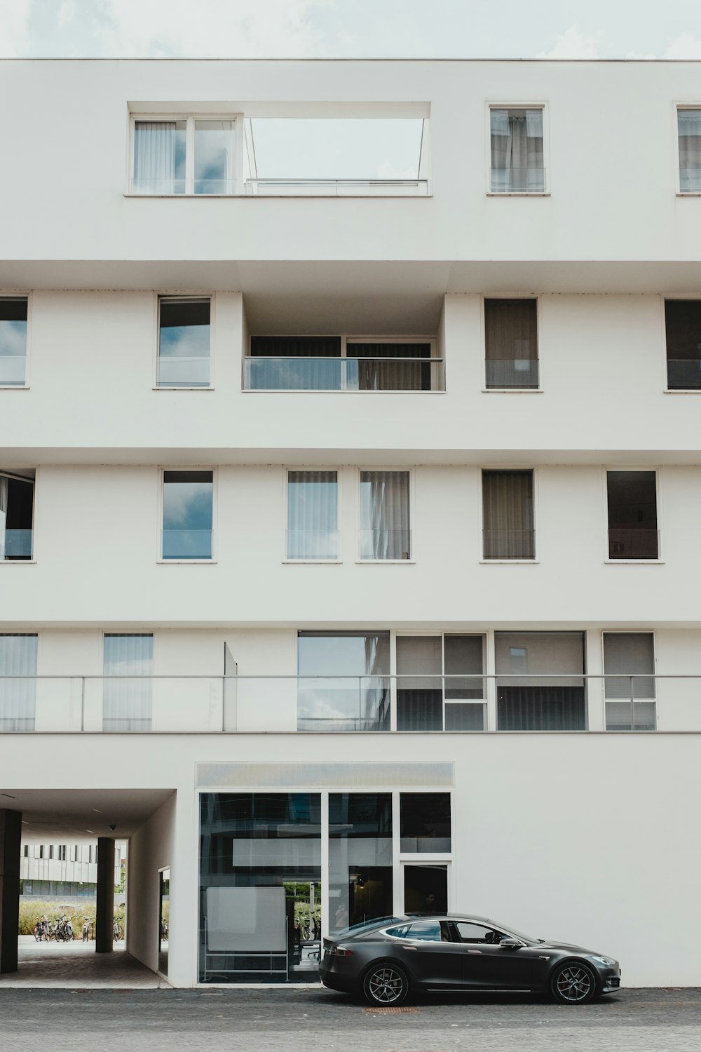 black sedan parked in front of white concrete building