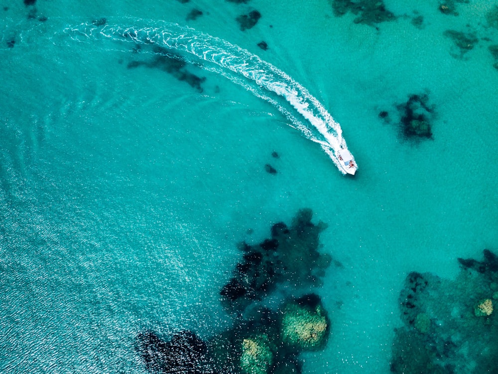 aerial photo of white yacht moving on clear body of water at daytime