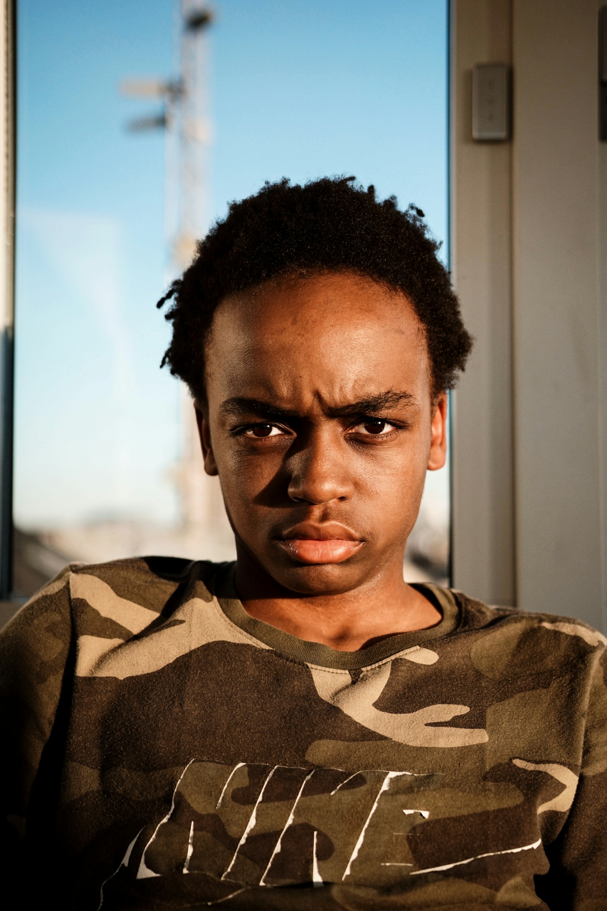 A man in a camouflage Nike shirt stares at the camera with a disapproving or unimpressed look.