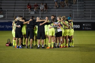 A dynamic soccer team huddled together on the field, showing unity and determination.