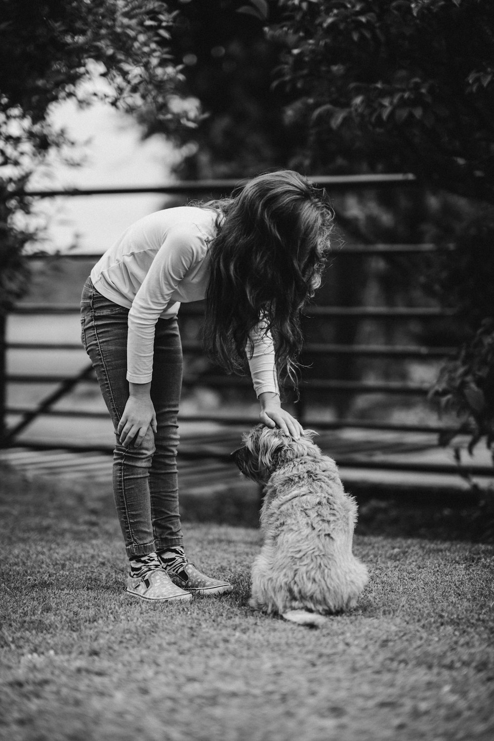 grayscale photo of girl tapping dog's head