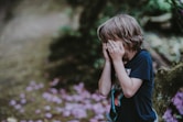 boy covering his face while standing