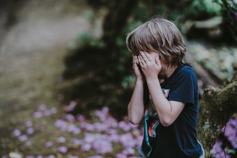boy covering his face while standing