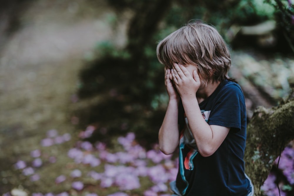 立ったまま顔を覆う少年