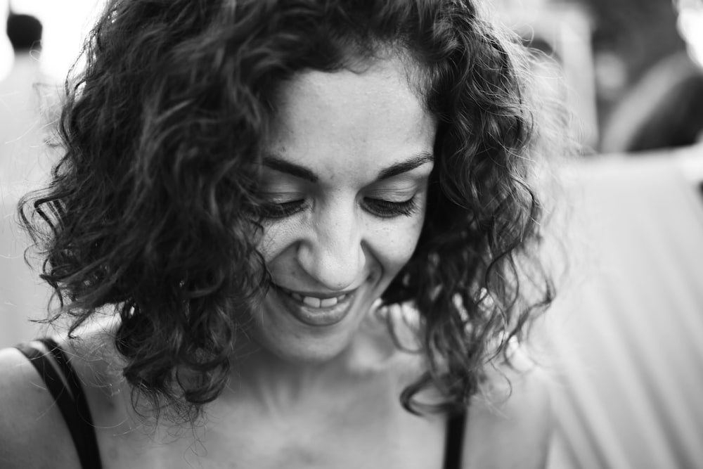 grayscale photo of smiling woman wearing spaghetti strap top