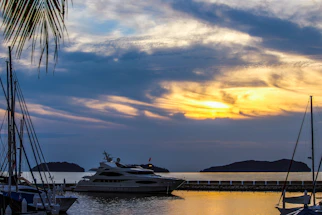 A romantic sunset view over a luxury yacht anchored in a serene Aegean bay.