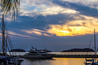 A luxurious yacht anchored near a serene tropical island at sunset.