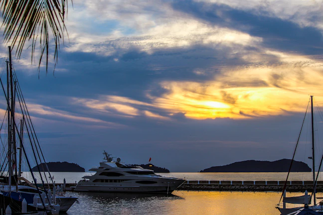 A serene private beach at sunset with a luxury yacht anchored nearby.
