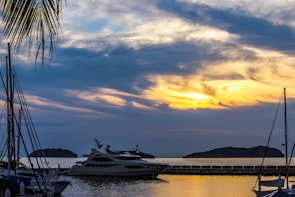 Sunset view of a luxury yacht anchored near a quiet Bahamas island with palm trees in the background.