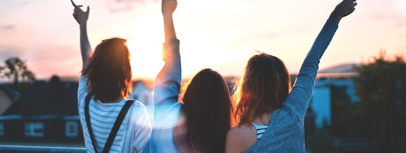 photo of three women lifting there hands \