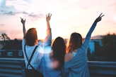 photo of three women lifting there hands \