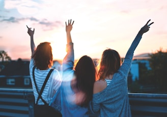 photo of three women lifting there hands \