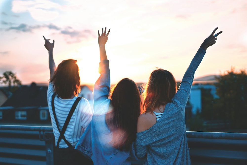 Three young women celebrating with their hands in the air