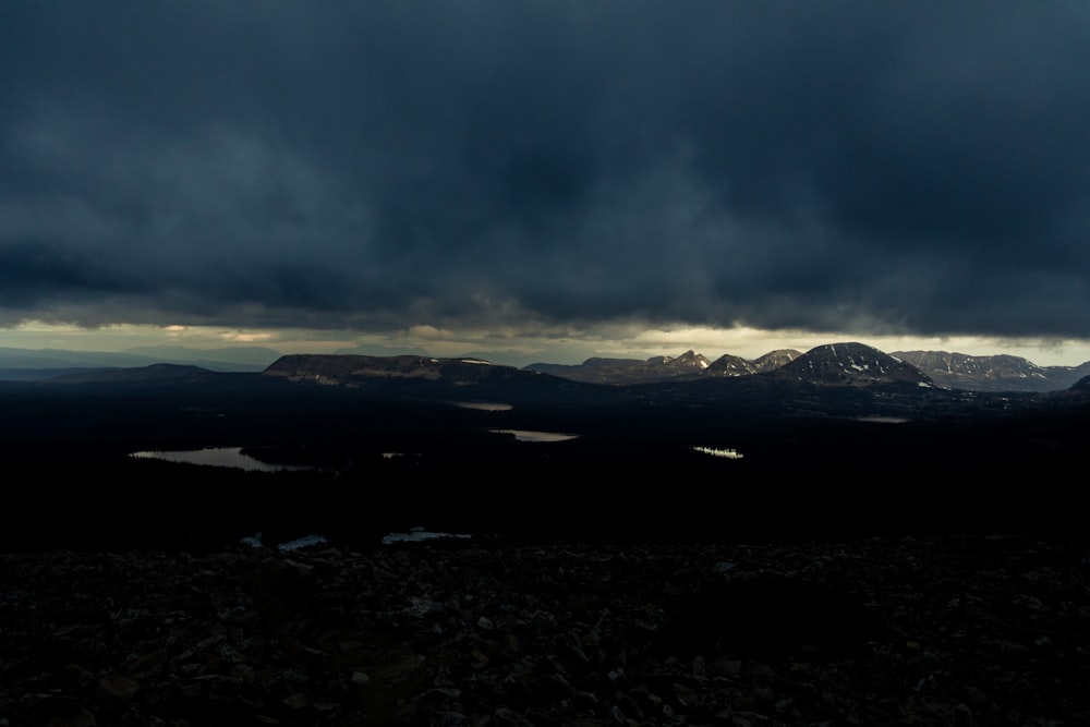 dark clouds hover over a mountain range as the sun sets