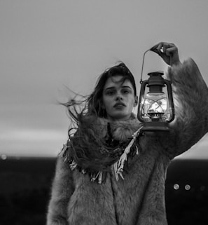 grayscale photography of woman holding lantern