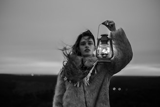 grayscale photography of woman holding lantern