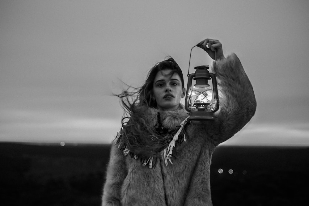grayscale photography of woman holding lantern