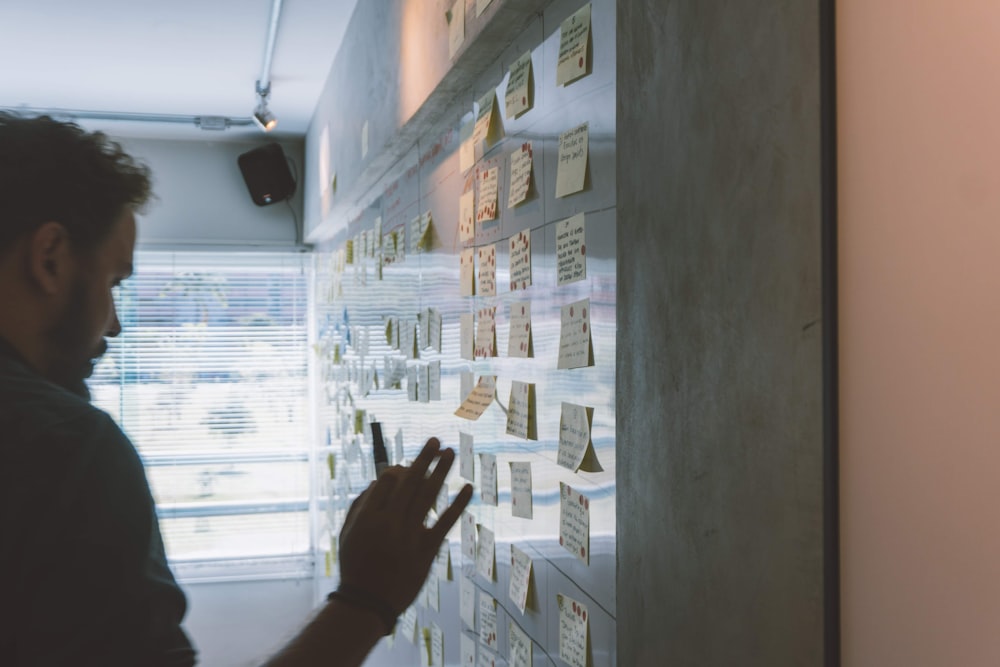 masculino poniendo notas adhesivas en la pared