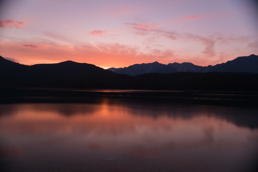 silhouette of mountain reflected on body of water