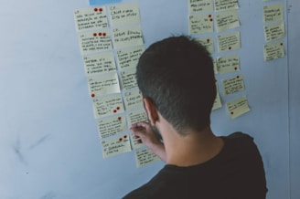 Close-up of hands arranging sticky notes on a Kanban board.