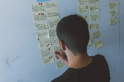 Close-up of hands organizing sticky notes on a project board.