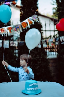 A cheerful child holding a colorful digital invitation with balloons in the background.