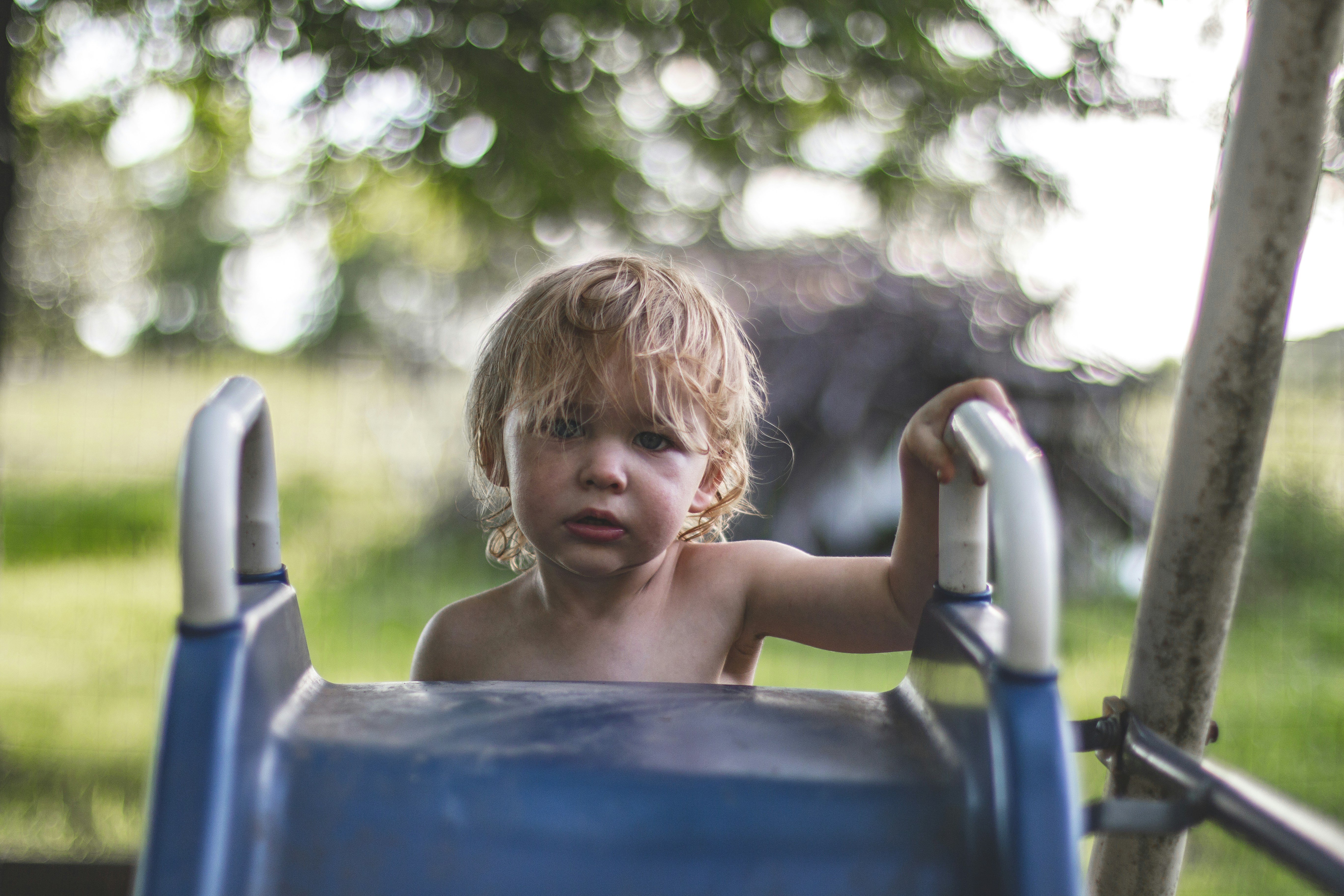 children climbing on slide, A rite of passage as a young boy makes his first climb to the top of the slide on his own. He know’s he has made a milestone of this day.