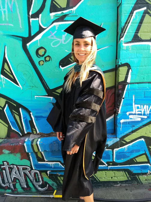 A creative graduation portrait featuring playful props and a unique urban backdrop.