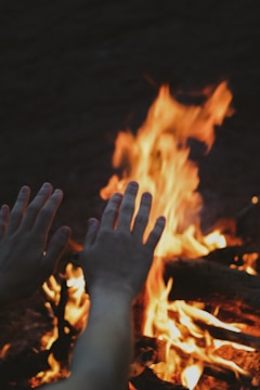 Close-up of hands around a campfire during an experiential journey.