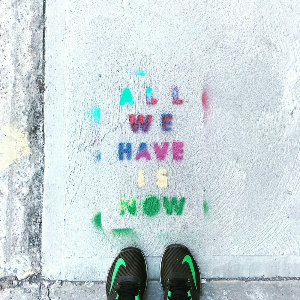 person standing on pavement with all we have is now written on it