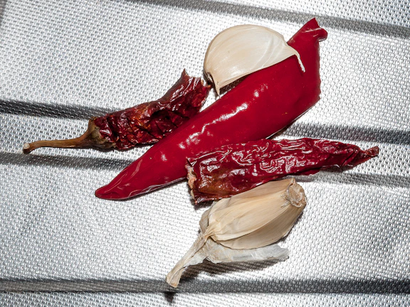 Close-up of fresh dried chilies and garlic ready for roasting on a rustic wooden table.