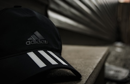 Close-up of a sleek black snapback hat with a minimalist logo, set against an urban graffiti wall.