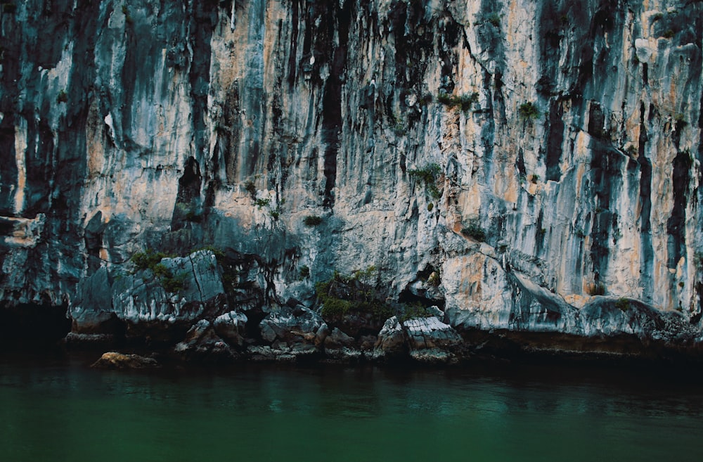 body of water beside gray cave