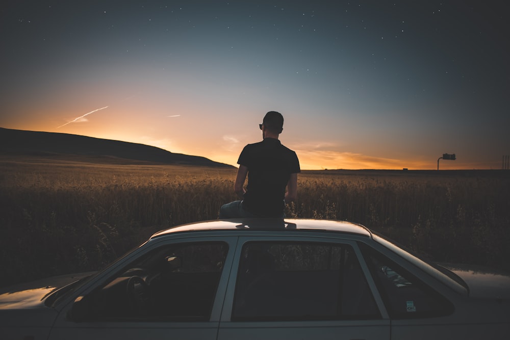 man sitting on gray sedan