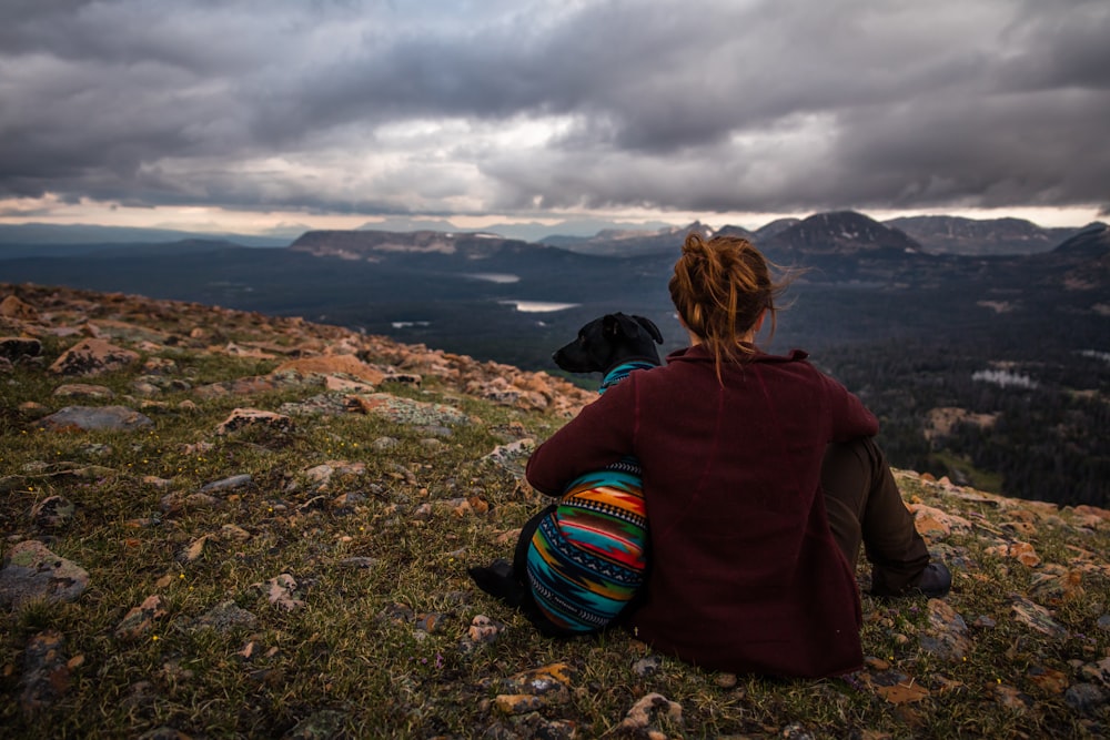 woman overlooking mountains while hugging dog