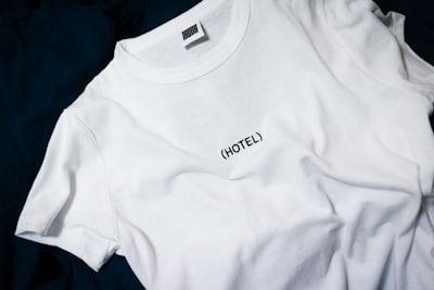 white hotel-printed crew-neck shirt on black surface clothe google meet background