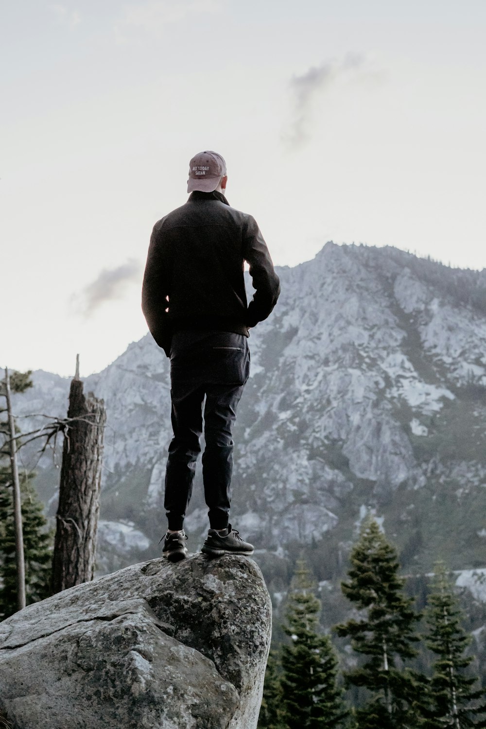 uomo in piedi sulla roccia grigia che guarda il picco della montagna